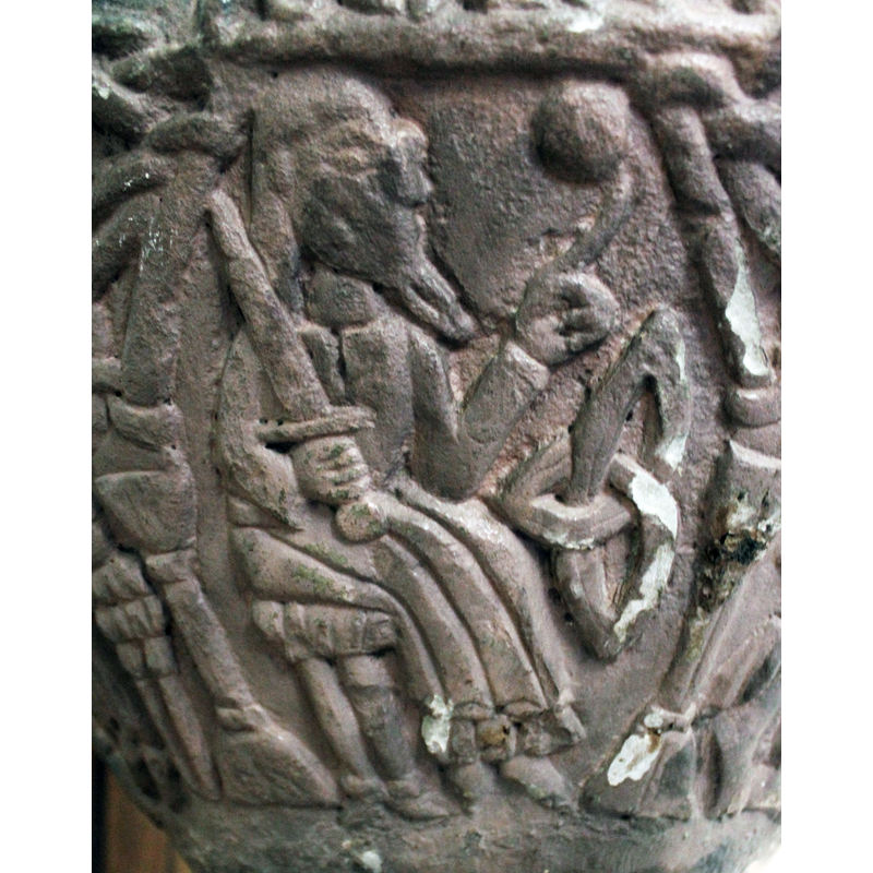 a figure, is a mirror image of the previous figure - can't tell if both male or female. It has a sword, exactly like the other one. To the right of the composition is a large symbol, triquetra, and a round bowl above it. The man point to the sphere.- maybe a star? No points however. He is bearded. [NB: identified as John and Stephen in SK: Gotland]