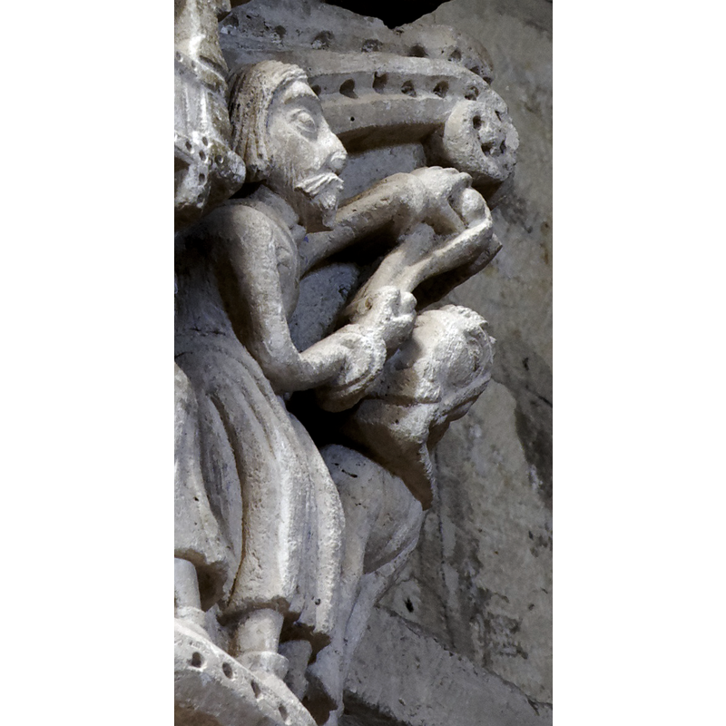capital on the north side of the chancel arch: on the left side of the capital is a mounted male holding an object and/with a flowing cloth in the right hand; the left hand hold the bridle and a ring, or the ring is secured to the saddle; the horse tramples over a fallen bearded man who appears unarmed; the front side of the capital has a balcony with two males in it looking out; below the balcony a male figure leans on a short pillar (to which he may be tied?); the right side of the capital has a bearded man loading a stone into his sling, by the side of a mounted knight armed with a lance and a shield, and wearing a helmet; behind him is an unidentified beast