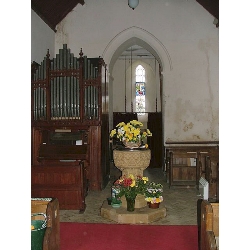 the modern font and cover ay the west end of the nave, just east of the tower arch