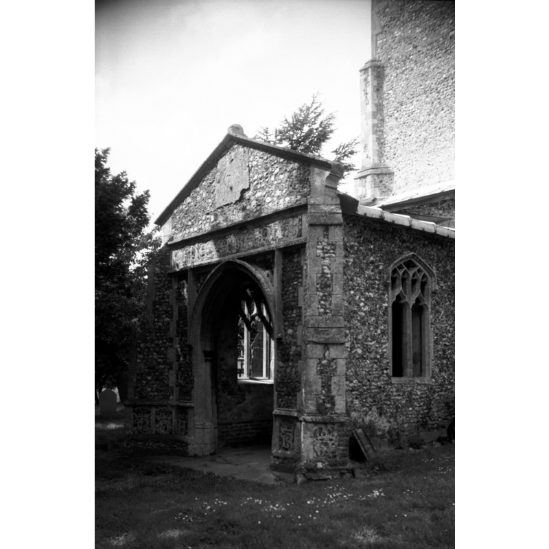 Photo caption: "Above the entrance a sundial and flushwork decoration reading IHS NAZARENES"