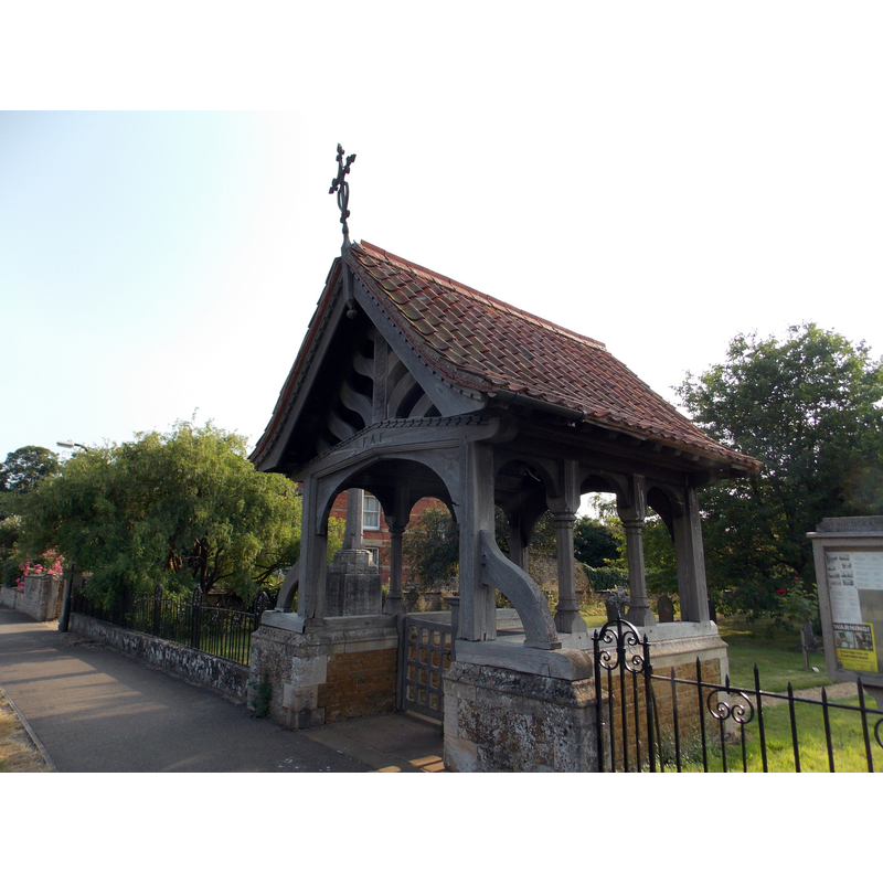 partiallly visible across the lychgate are the base and shaft of the 14th-century cross (restored in the 19th)