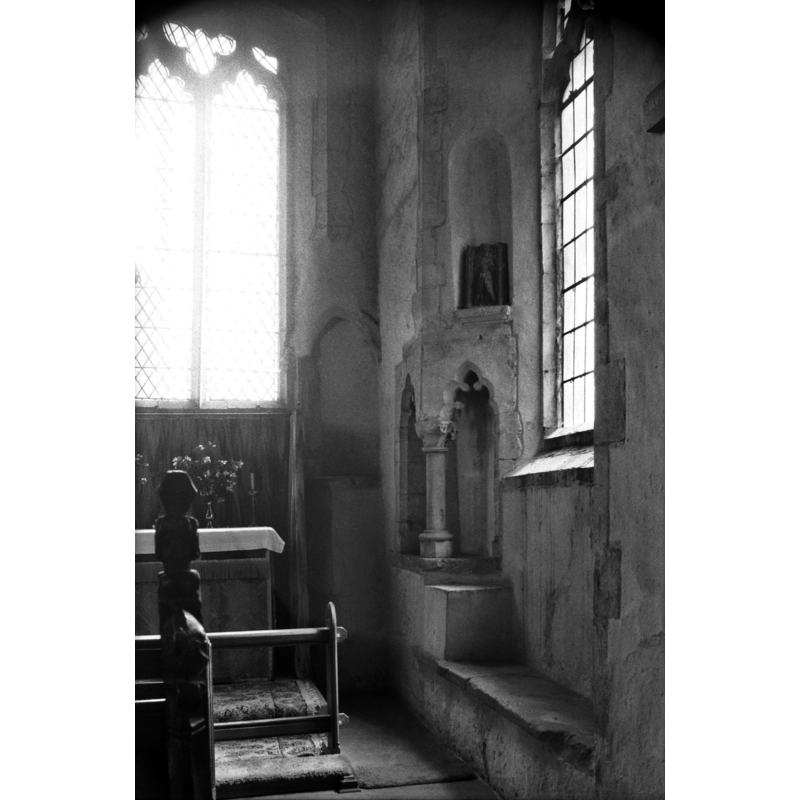 Photo caption: "Early 14c piscina and niche at SE angle of south aisle. Window recess sedilia"