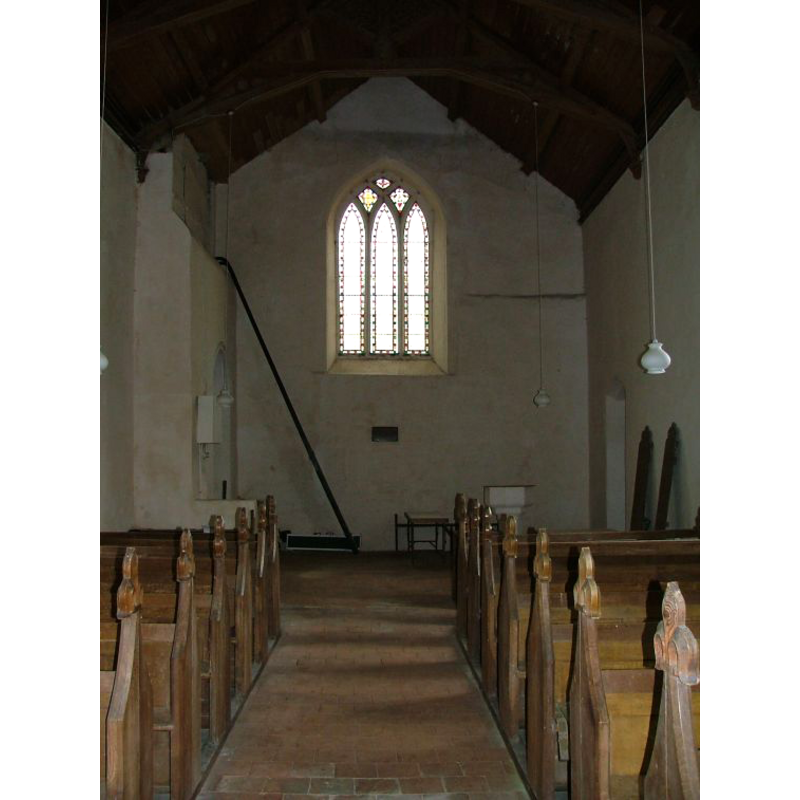 the top of the font is visible at the west end, behind the bank of benches on the right (north) side