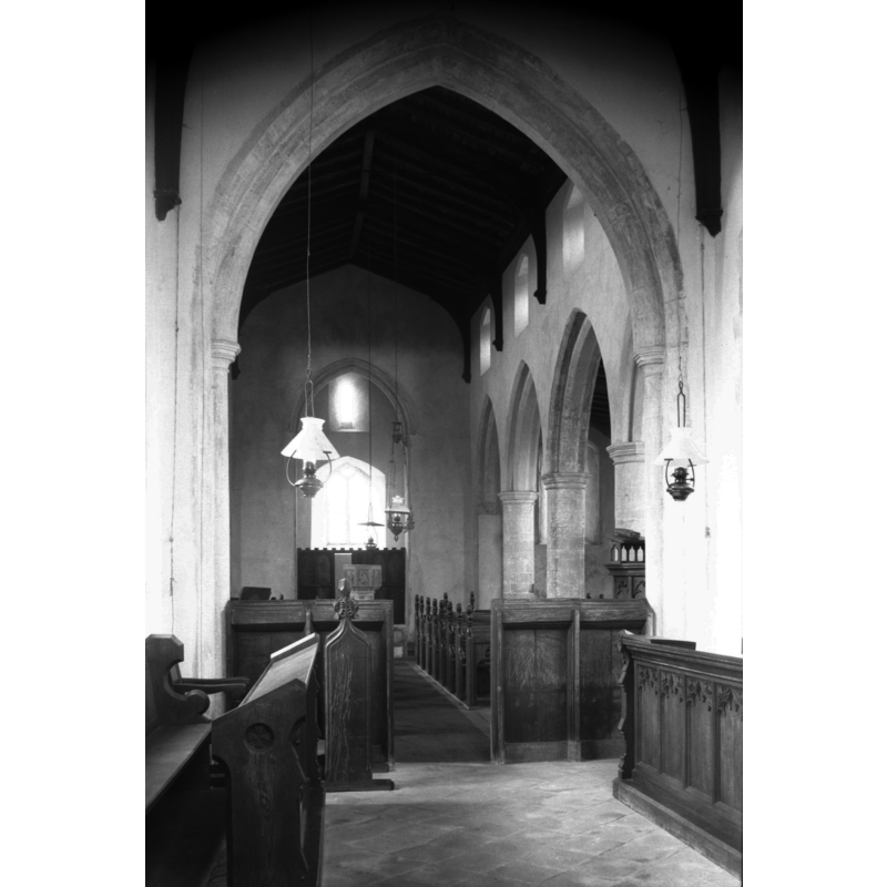 view west from the chancel; the font is partially visible at the west end -- Photo caption: "14c arcades with round piers"