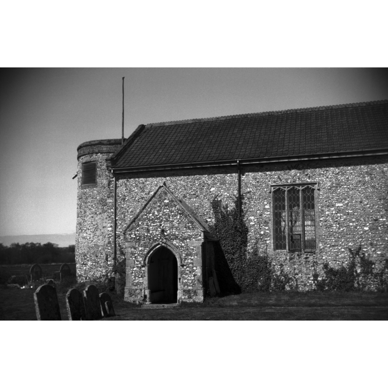Photo caption: "The Norman round tower is late and does not rise to the height of the ridge of the nave roof"