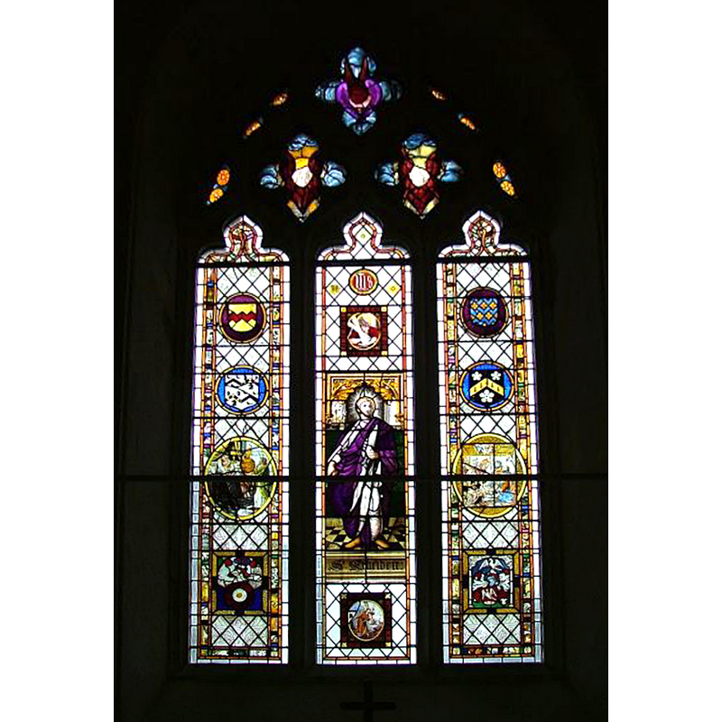 Knott (2005) writes: "Books credit it with being from Rouen cathedral, but actually it is much more interesting than that. It came partly from the collection of a Norwich antiquarian, partly from the Beauchamp Proctor family who donated similar glass to the churches at nearby Chedgrave and Langley. It was installed here in the 1820s. It does include some Rouen glass, but there is also a 15th century English Holy Trinity, and a set of Instruments of the Passion. The little roundels depicting one line homilies may well have come from the refectory of Langley Priory. Further, Chris Harrison tells me that there is surviving work here of the remarkable Lowestoft stained glass artist Robert Allen who was one of the earliest exponents of the medium in the years that the English were first rediscovering it. His are the eight Saints in the west window, as well as the Man of Sorrows in the south of the nave, St Andrew in the east window and a number of other pieces on the south side. Much of the rest is collected continental glass, but some of it is the work of Samuel Yarrington, who installed all the glass here in the church. Notably his is the church's Royal Arms of George IV, which are in glass on the north side of the chancel."