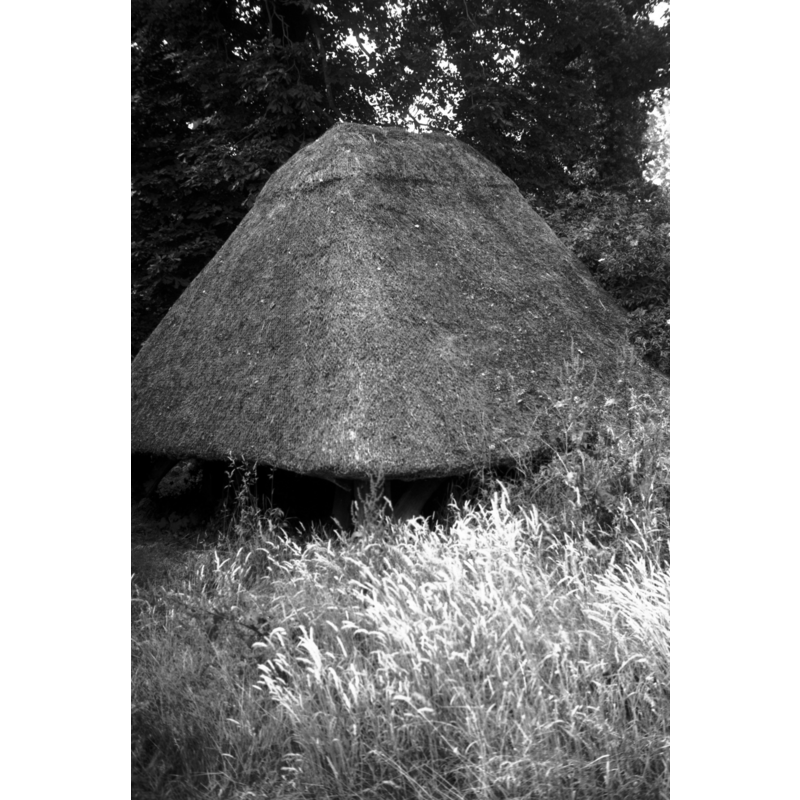 a bell 'cage' -- Photo caption: "The old bell frame from the fallen west tower stands in the NW corner of the churchyard, and is thatched"