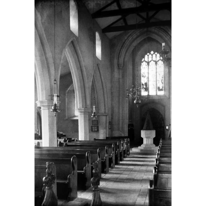 Photo caption: "15thc font" -- the font and its old cover are visible at the west end -- the old cover is no longer present in the church, and has been replaced by a modern one, octagonal and flat