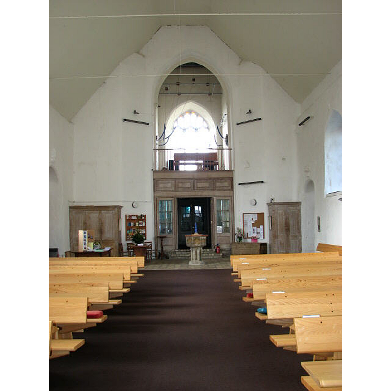 the interior of the reconstructed church after the 1981 fire; the font seen here was originally at the church of St. Miles Coslany, Norwich -- Photo caption: "On 19th March 1981 the church was gutted by fire during ongoing restoration work on the church tower, leaving only the tower and the curtain walls. Most of the interior, including memorials and font, were destroyed. The present furniture was designed and made in 2000 by John Barnard. The stained glass windows were designed by Sarah Bristow of Norwich in 1999/2000. The tower was built in 1447. It contains 6 bells, the tenor dating from 1261. This church is open every day"