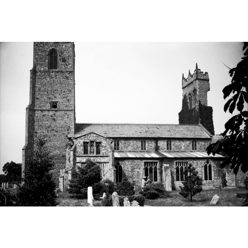 Photo caption: "15c tower with traceried sound-holes, and 15c porch with parvise above. Ruined tower of St Laurence to right"