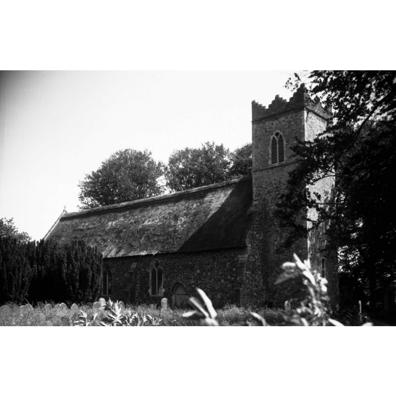 Photo caption: "The triple-stepped brick battlements of the tower are 16c. All but one of the windows are Decorated"