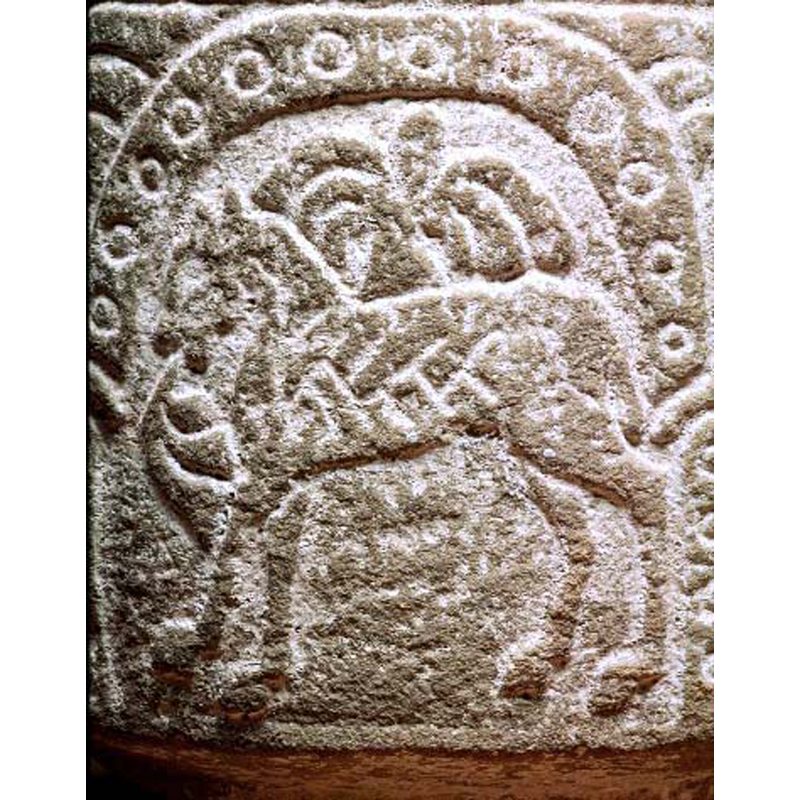 passant to the left; the animal has an acanthus-like tongue; a plant or tree shows behind the animal