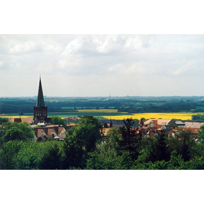 foreground left: Marienkirche Bergen; Stralsund at far back -- Photo caption : "Blick vom Rugard-Turm bis nach Stralsund. Im Vordergrund erkennt man den Stadtkern mit der Marienkirche. Am Horizont erscheinen die Kirchtürme von Stralsund, welche ca. 25km Luftlinie entfernt sind."