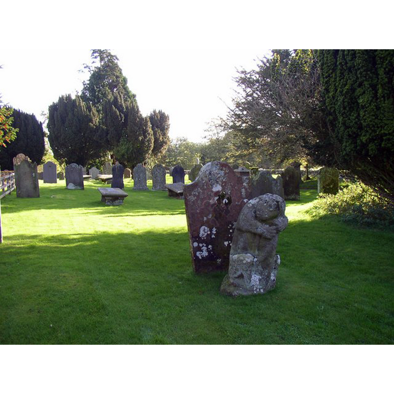 Photo caption: "Dacre churchyard. The four corners of the original churchyard (smaller than the present one) are marked by four medieval stone bears. They were studied by Chancellor Furguson in 1890, and he believed that they depict a legendary tale, which can be summarised by: bear sleeping, bear attacked by wild cat, bear shakes off cat, bear eats cat. The bear in this photo is the second in the sequence, but the cat has been worn away and we just see the bear looking over its shoulder."