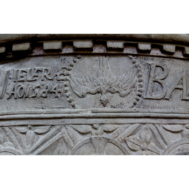 the dove from the Baptism of Christ has been incorporated into the upper inscription band