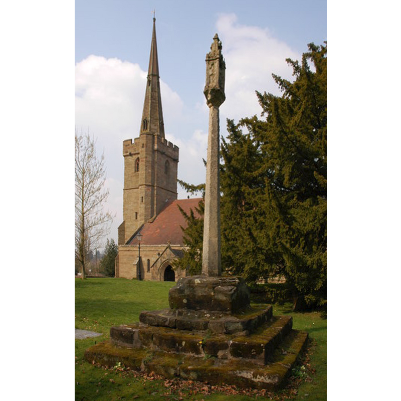 Source caption: "Preaching Cross, Belbroughton church. The base of this preaching cross dates from Saxon times, the shaft and capital date from 1900. Holy Trinity church can be seen in the background."