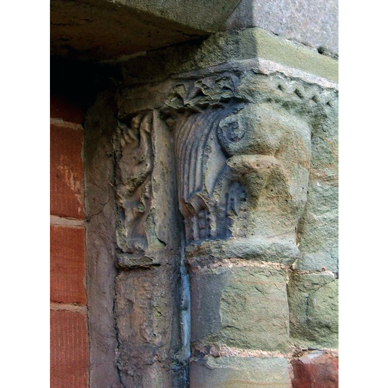 Source caption: "These carvings appear on the column on the right of the blocked door, on the church's south side. These are thought to be Norman, and probably have been re-used from another part of the church. There are also carvings on the door's other column, but they are so weathered that it is difficult to make out any real detail."