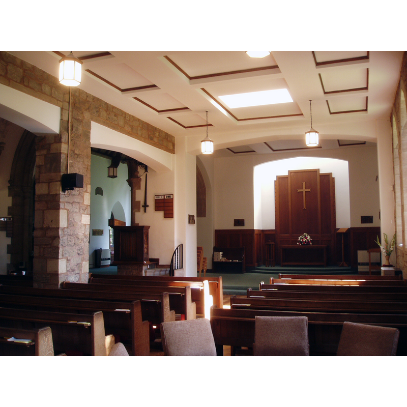 Source caption: "View along the south aisle at Chilvers Coton, rebuilt in the 1950s after the near destruction of the church by wartime bombing. The new aisle terminates in the chapel of the Three Kings, marked by a plain reredos in a recess, lit from above glass-bricks let into the ceiling."