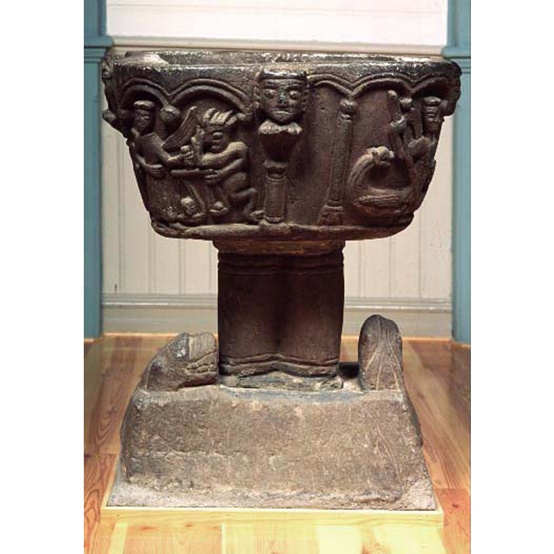 on the basin, left side, the weighing of the souls (?) by the angel, left, and the devil (right); pillar with large head in the concave centre; on the right is the scene with St. Michael (?) and a dragon; on the base the two animal protomes/heads