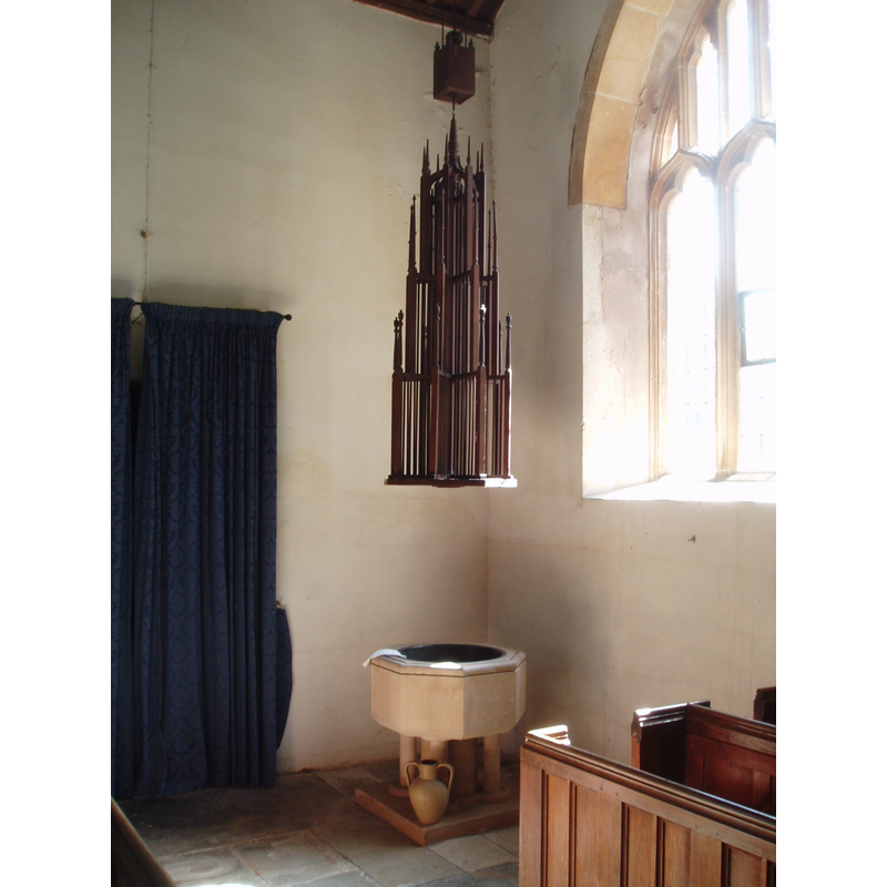 the modern font and cover at the northwest corner of the nave; the curtained doorway is the tower entrance