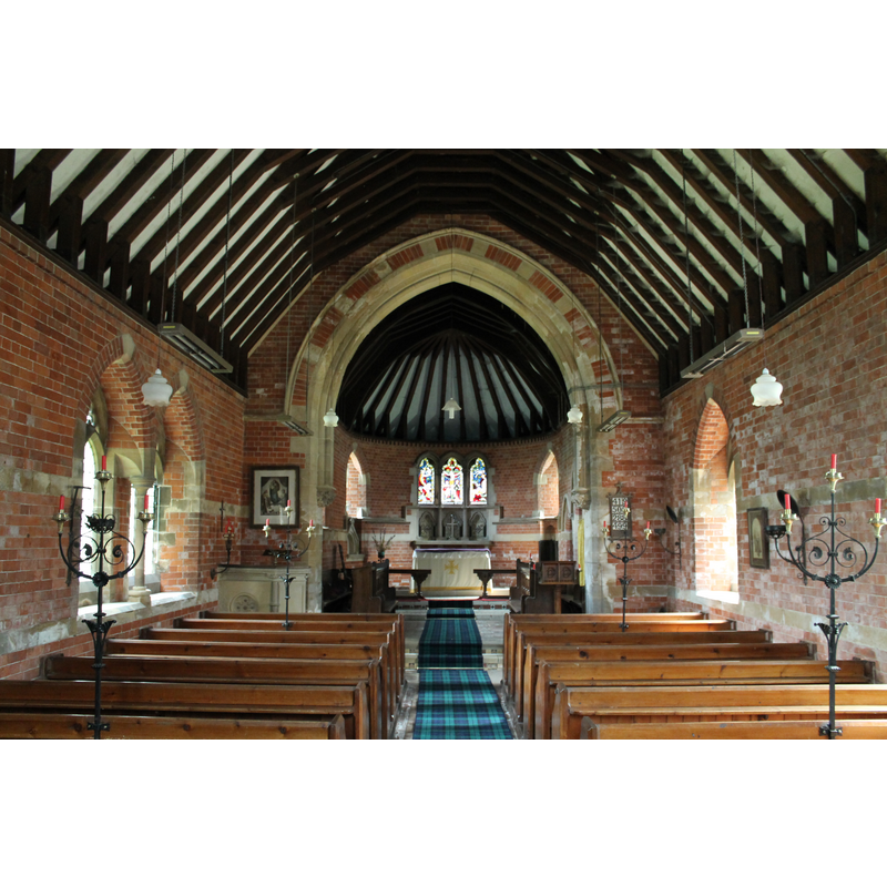 Source caption: "Interior, St Stephen's church, Hatton. St Stephen's is a small 19th-century church designed by Louth architect James Fowler (1828-1892). Built in 1871 on the site of a dilapidated medieval church, St Stephen is typical of many of the churches designed by Fowler. There is a nave, chancel, rounded apse, a turret with spirelet and vestry entrance and a south porch, all with steep slated roofs. The walls are of red brick (possibly from local brickworks) with bands of green sandstone. This stone was probably reclaimed from the old church and some blocks have weathered badly leading to some deterioration of brickwork. Inside, the roof is scissor-braced, the chancel is tiled, and there is some polychromatic brickwork in the chancel arch."