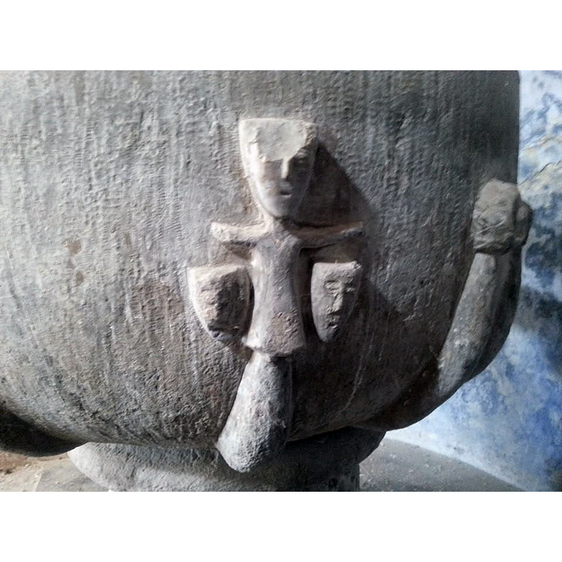 stylised, crucifix-like; a mask under each arm