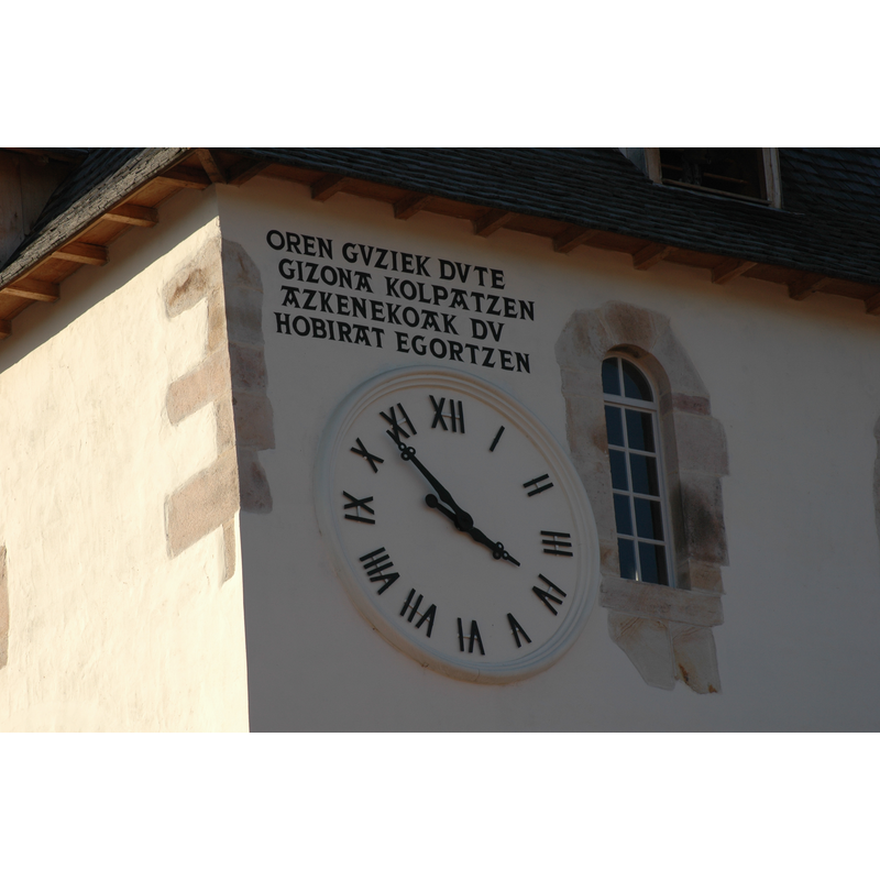 the inscription by the tower clock reads: "Oren guziek dute gizona kolpatzen azkenekoak du hobirat egortzen" [a Basque rendering of the Latin motto: "Omnes vulnerant, ultima necat"]