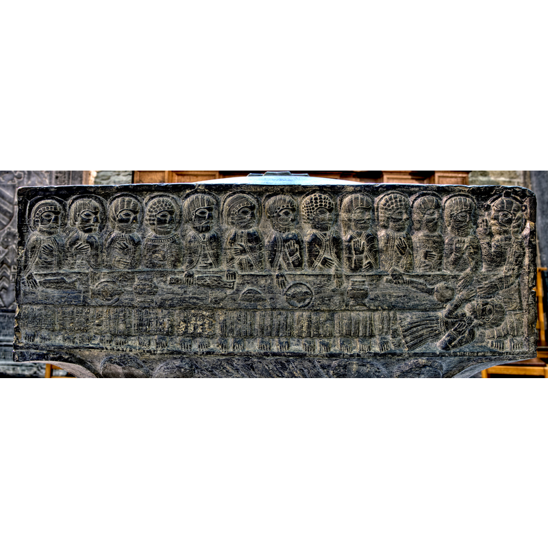 12 Apostles at the table with Jesus behind a food-laden table, plus one, non-nimbed, on the ground, horizontal, in front of the table; Judas?