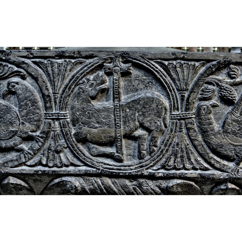 the cross here is almost identical to the one in the spandrel of the upper rim, with three floriated arms and a bead in its centre; the fourth arm of the cross goes all the way down to the hoof that supports it and is made of beaded tape; the 'lamb' is in passant-regardant pose; the centre circle has 3-strand pattern, while the other two are plain