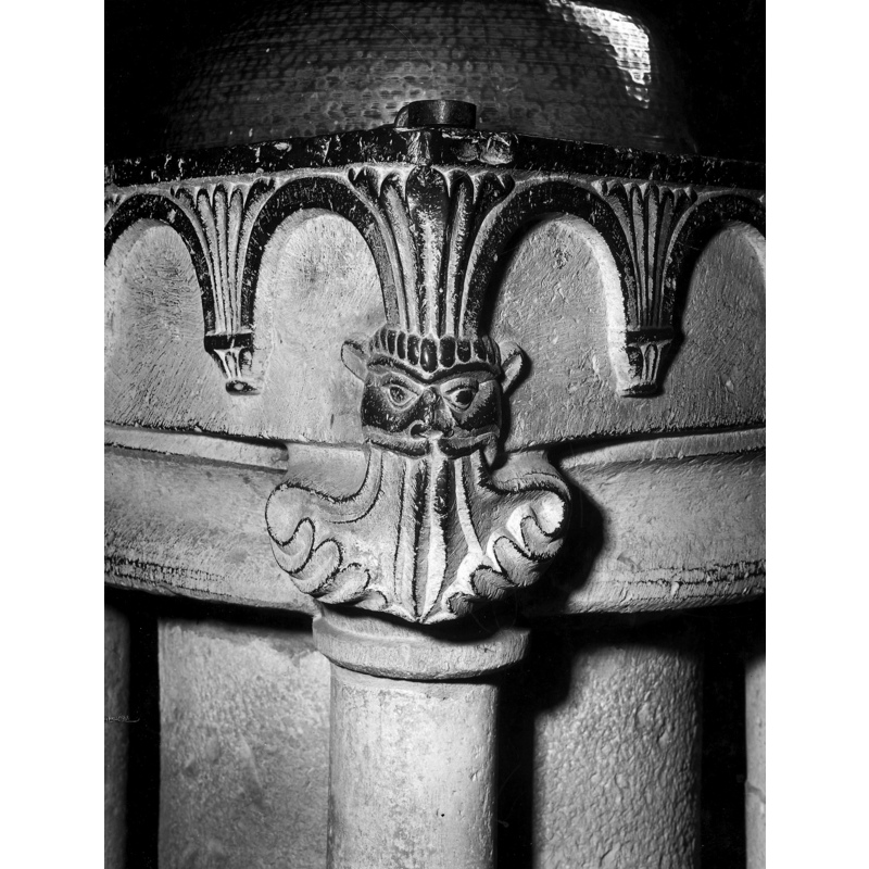 one of the four lion heads with vegetation stemming from the mouth at the angles of the underbowl