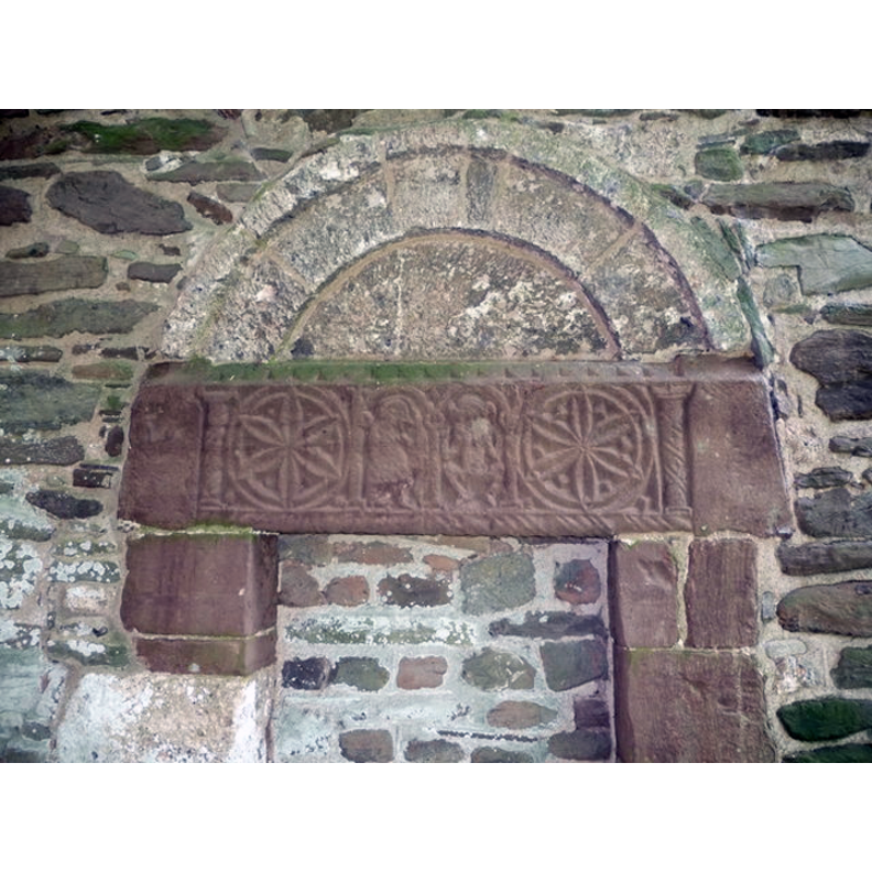 Source caption: "Old north doorway at St. Andrew's church, Bredwardine. The carved lintel here is pre-Norman in date and style and features a bird and a grotesque, more probably a sheela na gig."