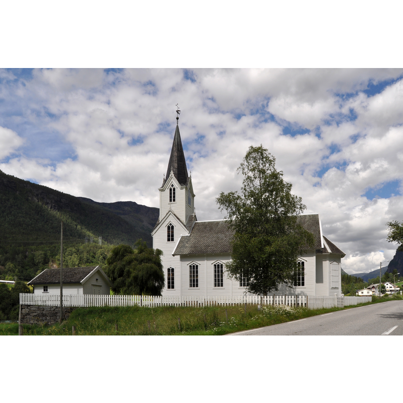 the new 19th-century church at Fortun, built in 1879 when the original wooden church of Fortun was removed and re-built in Fantoft, Bergen -- the modern font in this church was made by Torkjel Asheim, and bears an inscription around the basin top: "Lat småborni koma til meg - hindra dei ikkje for Guds rike høyrer slike til. Luk. 18,16."