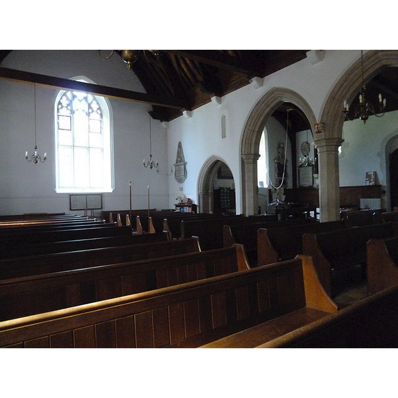 the top of the font can be seen through the middle arch, beneath the hanging bell rope