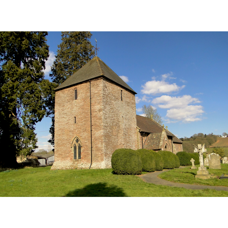 Source caption: "St Anna, Thornbury. The squat, unbuttressed West tower dates from the 13th century. F.R. Kempson added the somewhat intrusive West window in 1865-6 when he restored the church, rebuilding the chancel in the process and exposing the blocked 3-bay South arcade. Remote, but clearly loved and well cared for. Kempson added a shingled spire to the tower; this was replaced by the present pyramid roof in 1955."