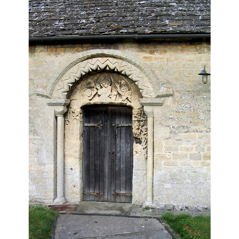 Source caption: "The south doorway has a Norman arch with a carved tympanum showing a demi-figure of Christ and two angels, a motif more usual in France than in England."