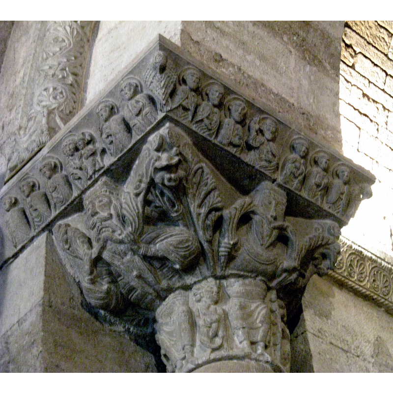 Source caption: "Linkes Kapitell aus dem Siegesbogen (Segnender Christus mit seinen Aposteln; in der Kapitellbasis ein Christus-Pantokrator) Romanische Kirche Santa Maria de Porqueres, Katalonien"
