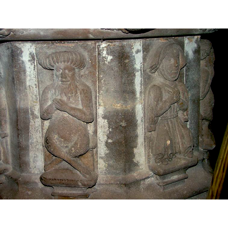 seen here on the right: a woman wearing a cowl and holding her hands in the traditional symbol of grief