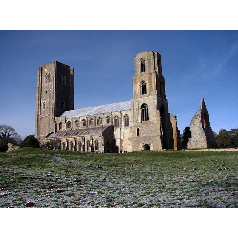 Source caption: "The church of St Mary & St Thomas of Canterbury, known as Wymondham Abbey, once used to be the church of a Benedictine Priory that once stood here. The Priory became an Abbey in 1448 but was closed by Henry VIII in the 1530s; its remains can still be seen in the adjacent field. The archway seen at right is one of the former doorways into the church. The church was completed during the 12th century. It used to be a cruciform church, with a length of 70 metres and twin west towers."