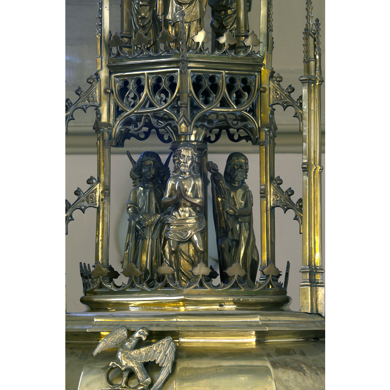 on the second volume of the font cover: from a crown-shaped base rises a high-Gothic canopy ot tracery open-work that houses the Baptism scene; the sides of the canopy itself are supported by the airiest of flying buttresses leaning on slender pillars with crocketed pinnacles