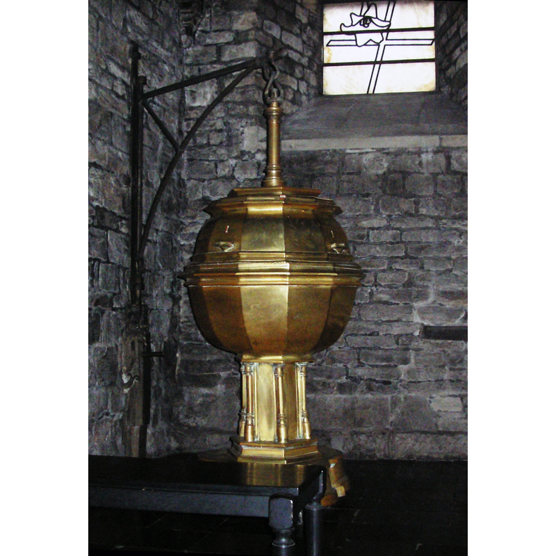 Source caption: "Basilica of Our Lady, Maastricht, the Netherlands. Interior Westwerk with baptismal font (stripped of ornaments) by Aert van Tricht. Modern leaded-glass window by Marien Schouten." -- with the wall-mounted crane in place