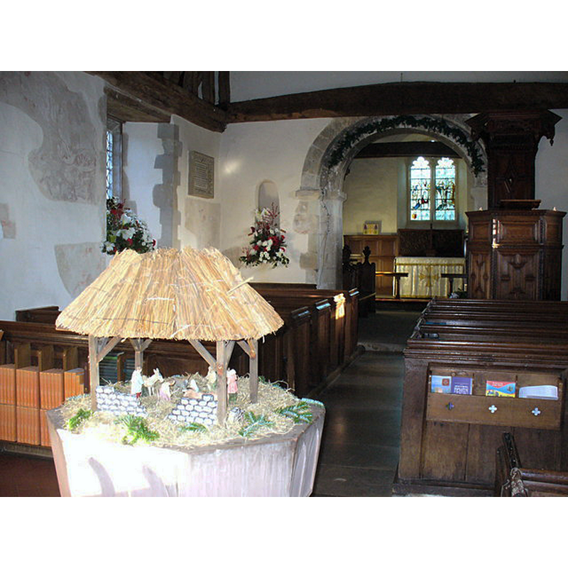 Source caption: "Inside Pyrford Church. Looking from the Christmas nativity scene towards the East Window. Note medieval fresco on the wall to left and the round Norman arch over the aisle."