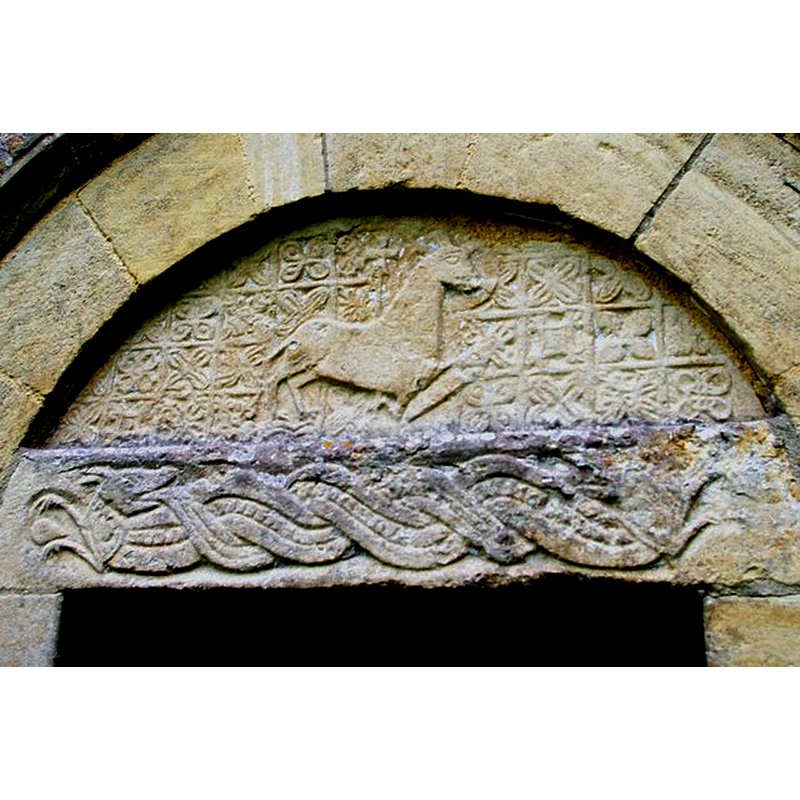 Source caption: "Agnus Dei. Norman tympanum to the north priest's doorway of St Giles' Church. The Lamb and Cross have a background of ornamental diaper and a pair of Viking dragons entwined in mortal combat lurk on the lintel beneath."
