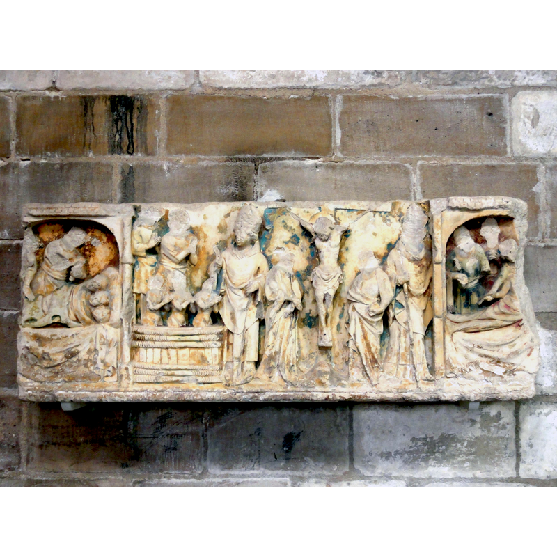 Source caption: "Retable de Saint-Nicolas, du XIVe siècle, probablement incomplet." -- Listed in Palissy [ref.: PM60001457: "Le retable illustre des scènes de la vie de saint Nicolas et de la Passion du Christ (Christ en croix entre la Vierge et saint Nicolas). De gauche à droite : - Le boucher s'apprête à égoger les trois enfants endormis -Le saint en costume d'évêque ressuscite les enfants dans le saloir, - Christ en croix entre la Vierge et saint Jean, - Saint Nicolas passe une bourse par la fenêtre. [...] Lors de son classement, l'oeuvre a été datée du 15e siècle, mais les drapés fluides, les silhouettes des figures autorisent à la dater du 14e siècle. C'est une sculpture de belle qualité. Le retable ne semble pas complet. [...]  Presque tous les visages ont été bûchés. Restauration par Geneviève Rager (Paris) et l'entreprise Charpentier PM (Paris) en 1994."