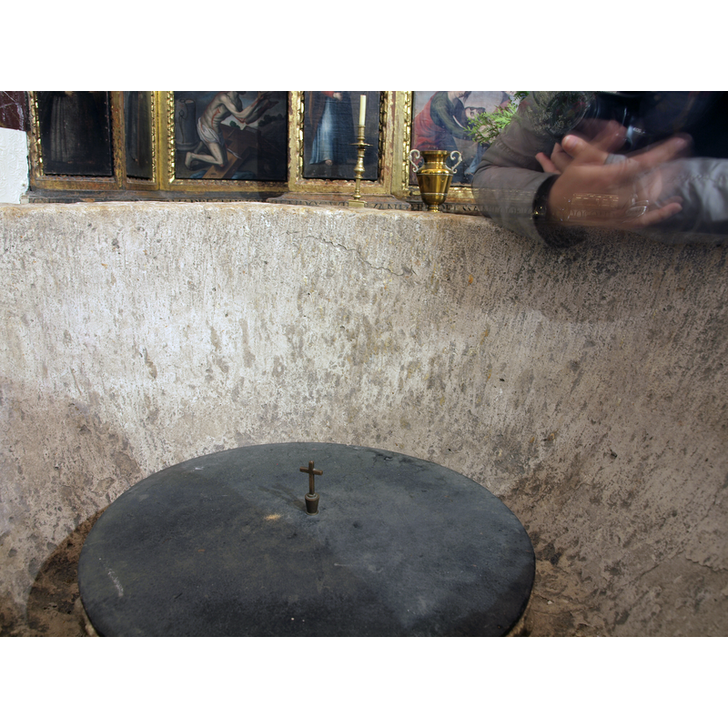 the covered object inside is probably a modern insert used to hold a limited amount of holy water for baptisms