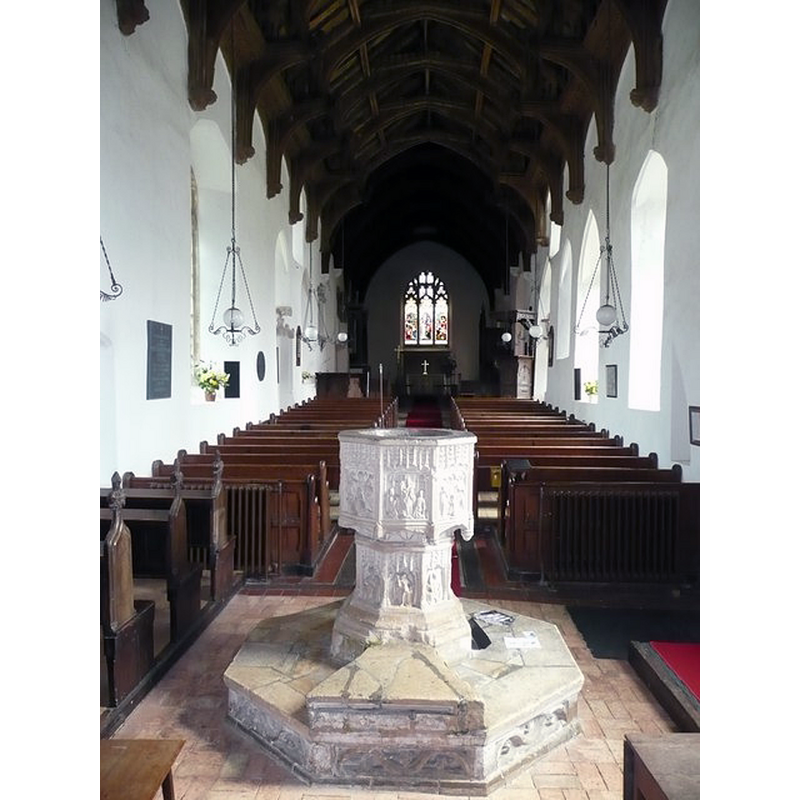 at the end of the nave, looking east -- Source caption: "Font and nave, St. John the Baptist's church. The nave roof and the Seven Sacraments font are Badingham's greatest treasures, but the visitor will probably be first struck by the fact that the nave floor slopes upward: rising twenty five inches from the font to the chancel steps."