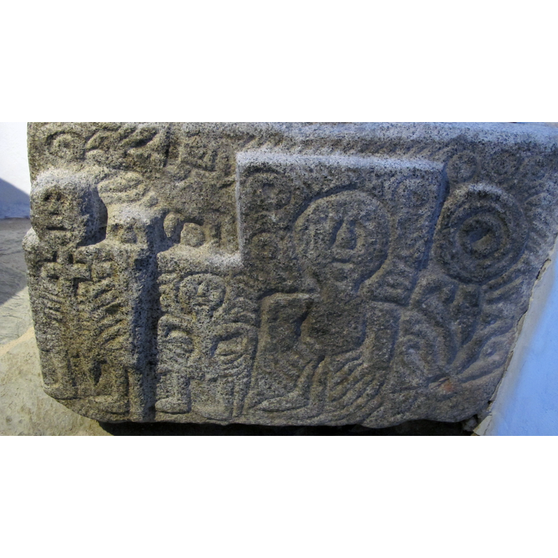 on the upper side, above the two figures on the left