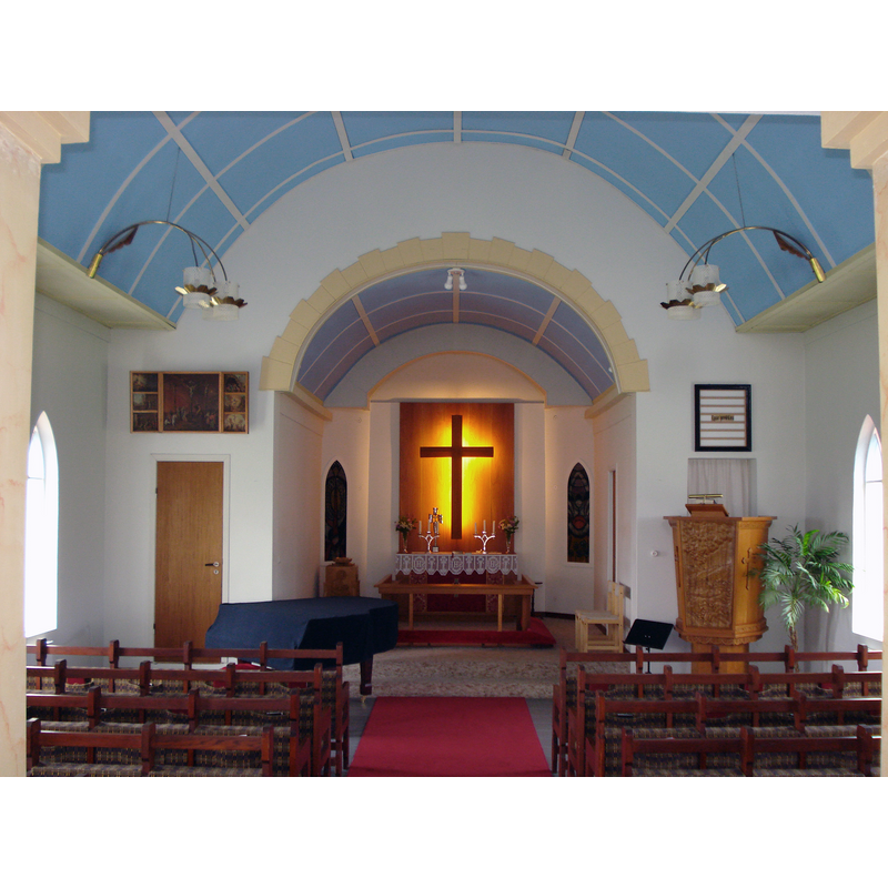 the interior of the modern church re-built mid-20thC -- Source caption: "Reykjahlíðarkirkja er í Skútustaðaprestakalli í Þingeyjarprófastsdæmi. Reykjahlíð var bær og kirkjustaður en nú smáþorp og mikill ferðamannastaður við Mývatn norðaustanvert. Kirkjan, sem nú stendur, var byggð 1958-1962. Hún tekur 120 manns í sæti. Skírnarsá, sem Jóhannes Björnsson á Húsavík skar út auk myndskurðar á prédikunarstólnum. Batikmyndirnar í kórnum eru eftir Sigrúnu Jónsdóttur."