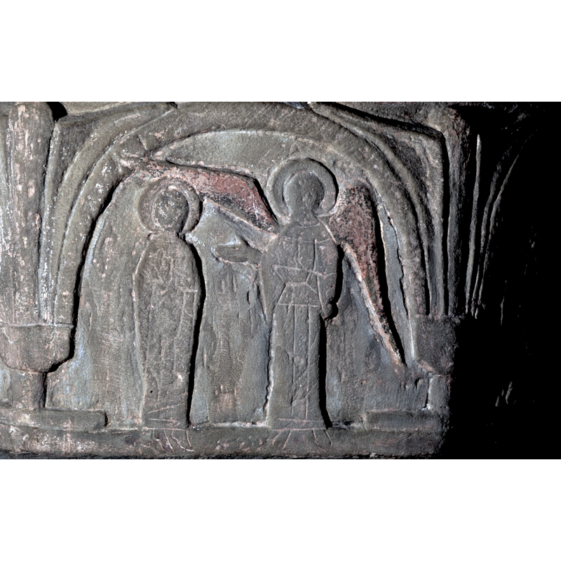 on the northwest side of the basin -- Gabriel stands to the right of the composition - wings spread out and apart, dominating the composition. The Virgin stands to the left. Her hands are in prayer gesture. Paint remains indicate that three bushes were present in this scene. One in the middle, between Gabriel and the Virgin, and one on either side of the two figures. These were once painted in the scene not carved. The carving of this scene is kept to a minimal. The feet of the two figures have been incised into the lower frame.