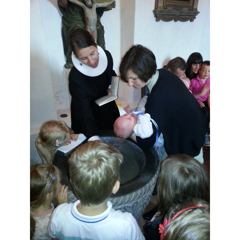 the medieval font still in use at present with Sognepræst [vicar] Malene Guassora officiating a well-attended baptism