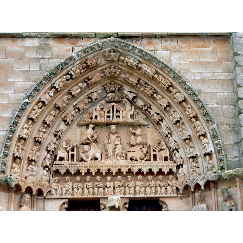 Source caption: "La portada muestra en el tímpano a Cristo entronizado dictando su palabra a los 4 Evangelistas, sentados a su alrededor en pupitres. Rodean la imagen del Salvador los 4 tetramorfos nombrados en el Apocalipsis que están al lado del trono del Juez supremo: el león, el toro, el águila y la figura humana. Por debajo, en el dintel que sostiene el tímpano se representa a los doce Apóstoles en conversación por parejas. Todo ello enmarcado por tres arquivoltas apuntadas recargadas de figuras de ángeles y reyes músicos que forman una verdadera orquesta celestial."